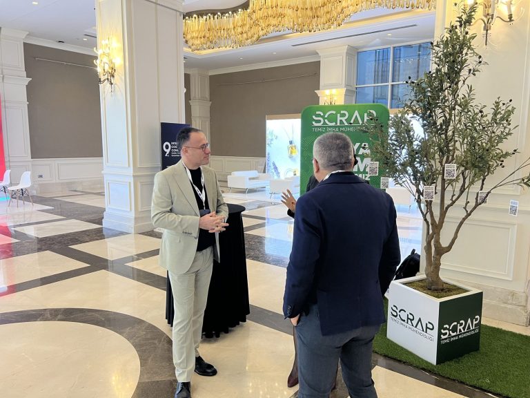 Participants chatting beside an olive tree in a Scrap-branded planter and the Dünya Bizim İş Ortağımız banner at the 9th International Cosmetics Congress.