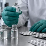 Laboratory inspector examining medicine vials and blister packs. Illustrative image.
